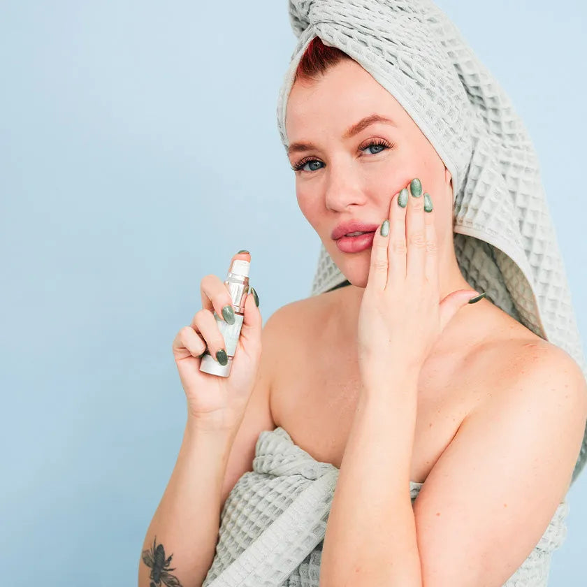 Woman in towel applying Bohemia Skin serum for clean, holistic skincare on face