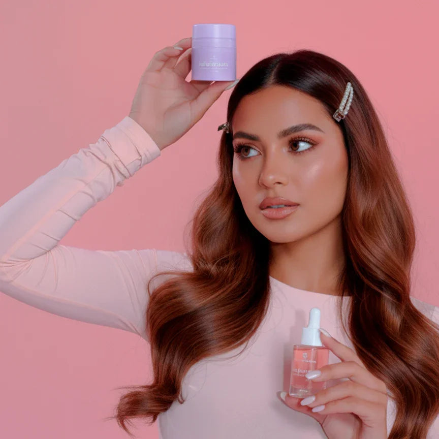 Woman holding Bohemia Skin skincare products against a pink background, glowy complexion