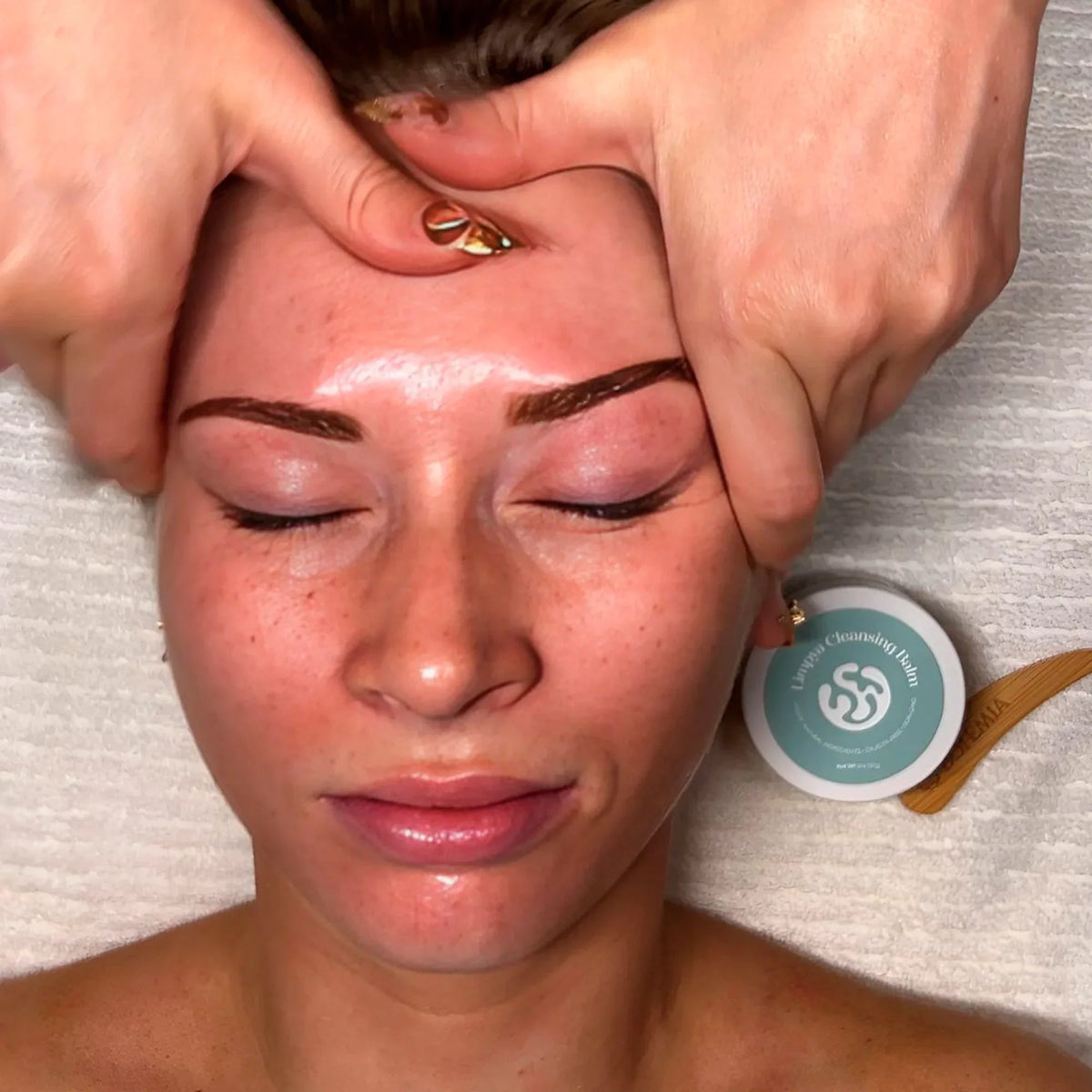 Facial massage with Bohemia Skin cleansing balm, woman relaxing on spa towel.