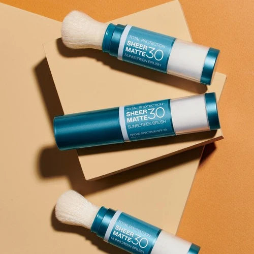 Three Colorescience Sunforgettable Total Protection Sheer Matte SPF 30 sunscreen brushes arranged on an orange background.